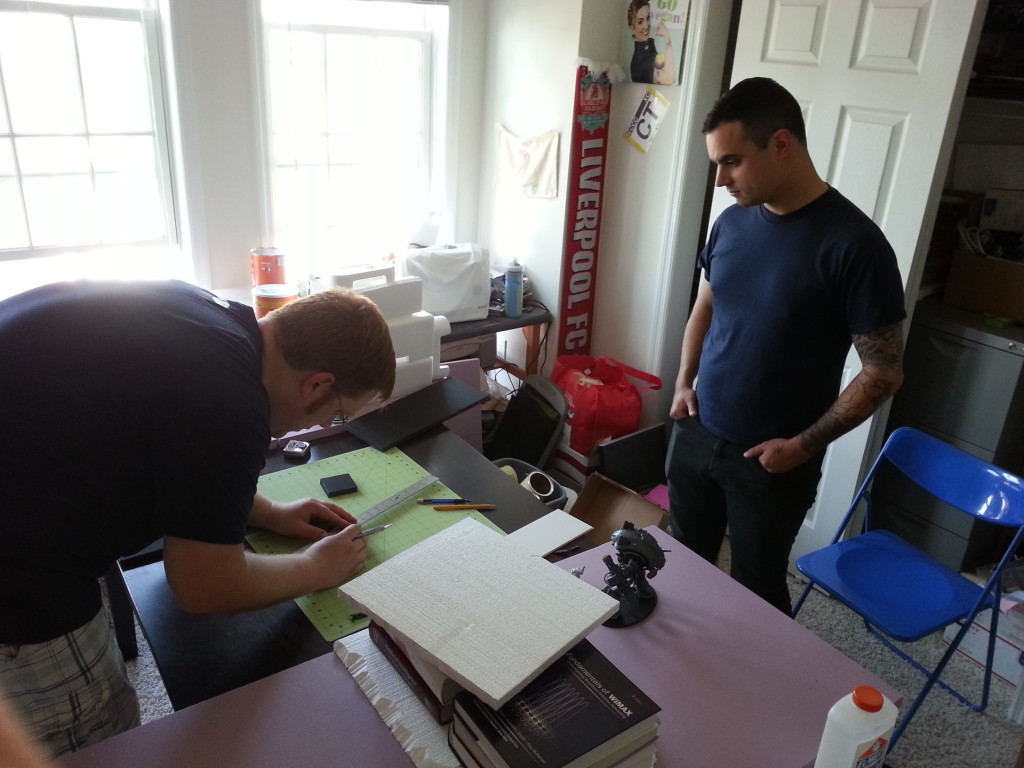 Colin measures and cuts some foam as Jason supervises.