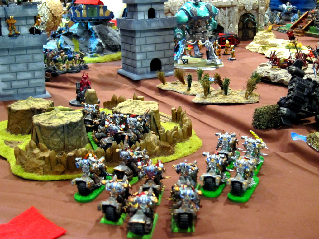 Traitor melta-bikers race through a slave village toward a Knight Errant threatening their perimeter bastions.