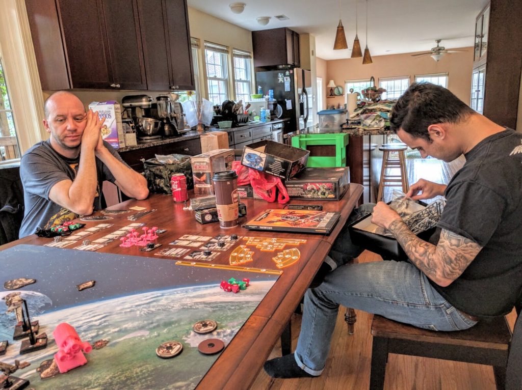 Matt ponders game balance as he watches a VIP Escort playtest, while Jason stays firmly focused on the grimdark.